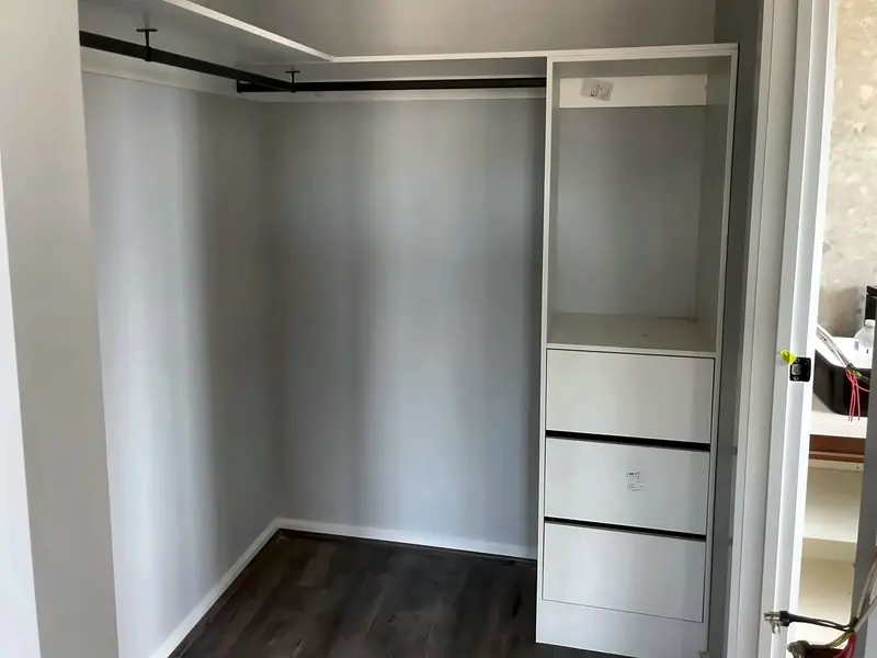 Walk-in robe with a white drawer tower and black hanging rails, by Maya Cabinets in Melbourne
